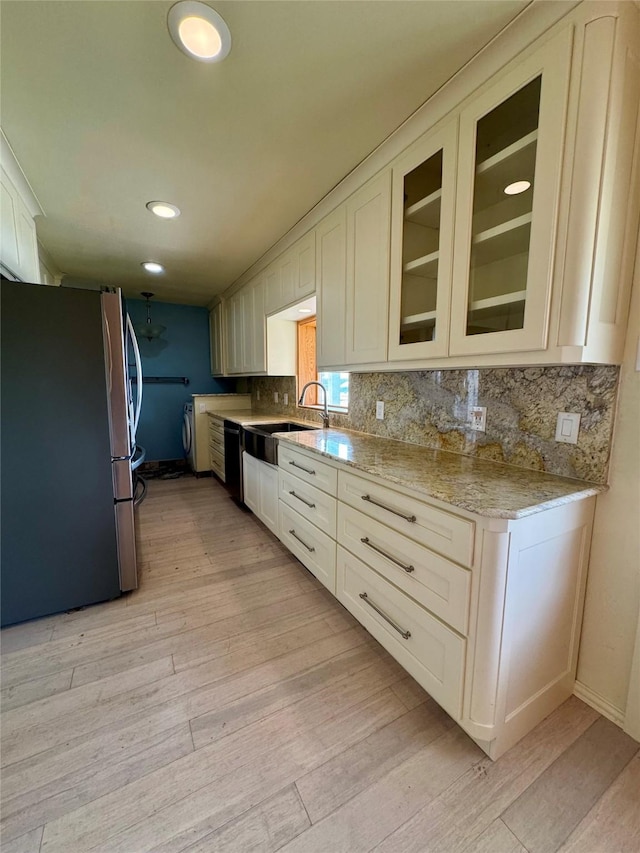 kitchen featuring light hardwood / wood-style flooring, light stone countertops, stainless steel fridge, sink, and tasteful backsplash