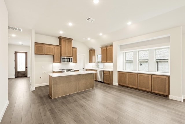 112 Woodlands Way, Balch Springs, TX 75181 - kitchen with appliances with stainless steel finishes, brown cabinets, a kitchen island, plenty of natural light, and recessed lighting