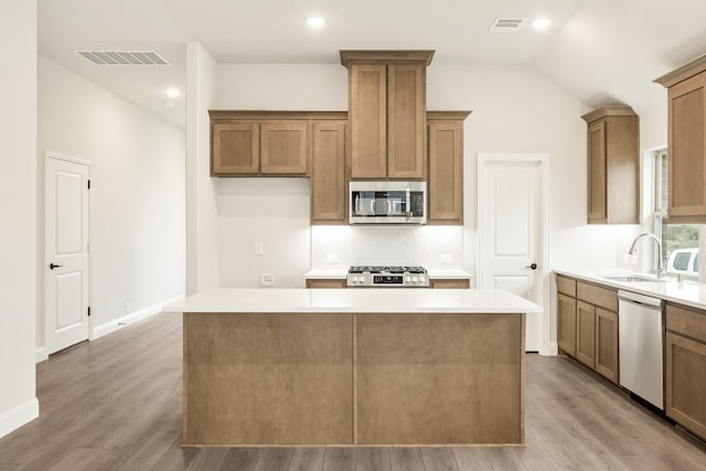 112 Woodlands Way, Balch Springs, TX 75181 - kitchen featuring stainless steel appliances, a sink, a center island, light wood-style flooring, and tasteful backsplash
