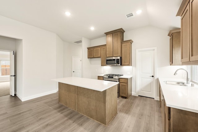 112 Woodlands Way, Balch Springs, TX 75181 - kitchen featuring appliances with stainless steel finishes, a sink, light wood-style flooring, a kitchen island, and light countertops