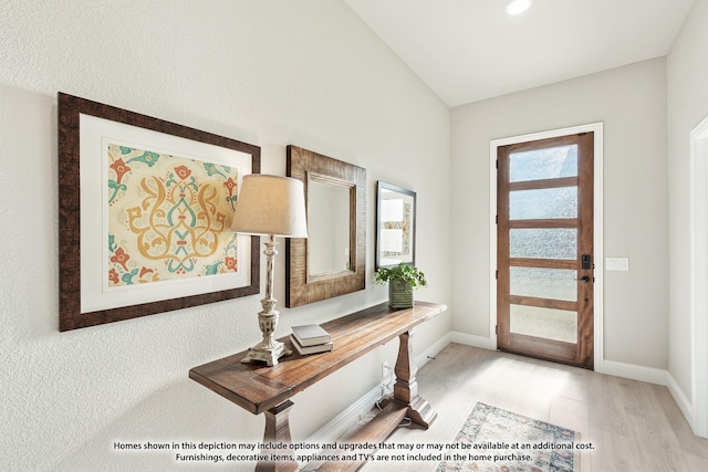 foyer featuring light wood-type flooring and lofted ceiling