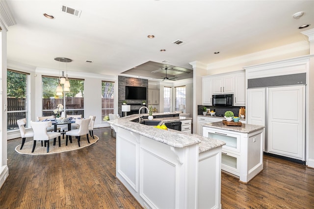 kitchen with sink, white cabinetry, dark hardwood / wood-style flooring, hanging light fixtures, and a kitchen island with sink