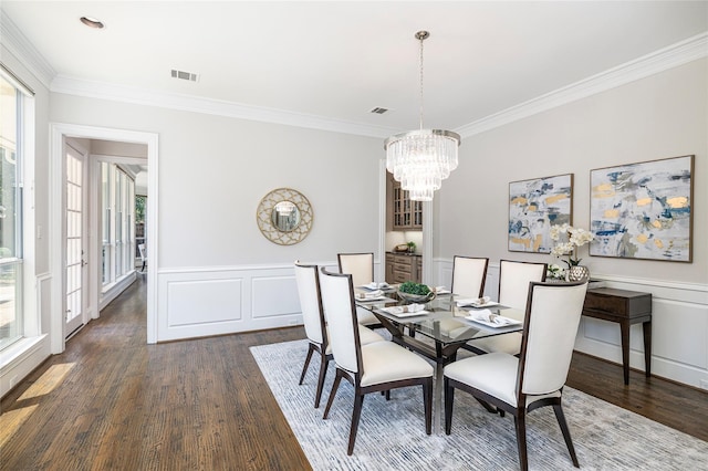 dining space with an inviting chandelier, crown molding, dark wood-style flooring, and wainscoting