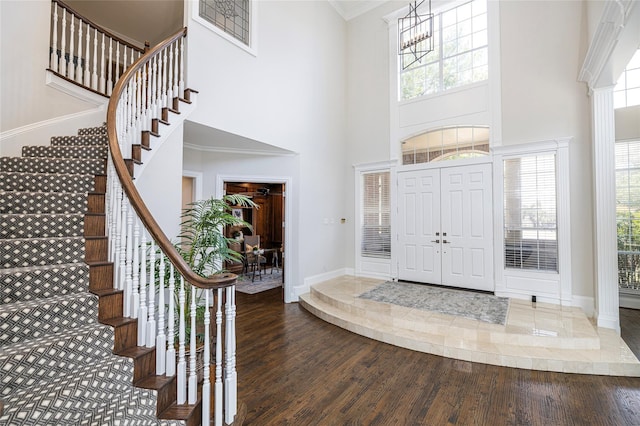 entryway with a high ceiling, dark wood-type flooring, crown molding, and a healthy amount of sunlight