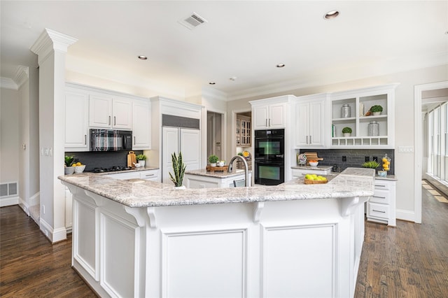 kitchen featuring light stone counters, a large island with sink, white cabinetry, dark hardwood / wood-style flooring, and black appliances