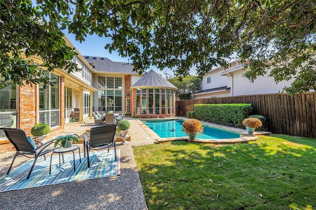 view of swimming pool featuring a patio area, a lawn, and a sunroom