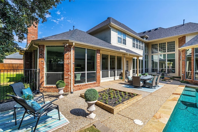 back of property with a fenced in pool, a patio, and a sunroom