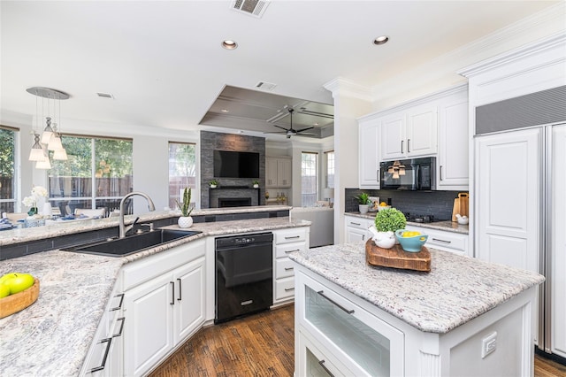 kitchen featuring plenty of natural light, light stone countertops, white cabinets, black appliances, and sink