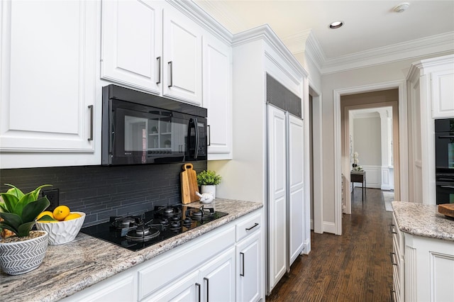 kitchen featuring backsplash, crown molding, black appliances, white cabinets, and light stone countertops