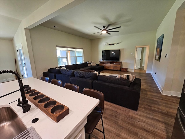 living area featuring dark wood finished floors, a ceiling fan, and baseboards