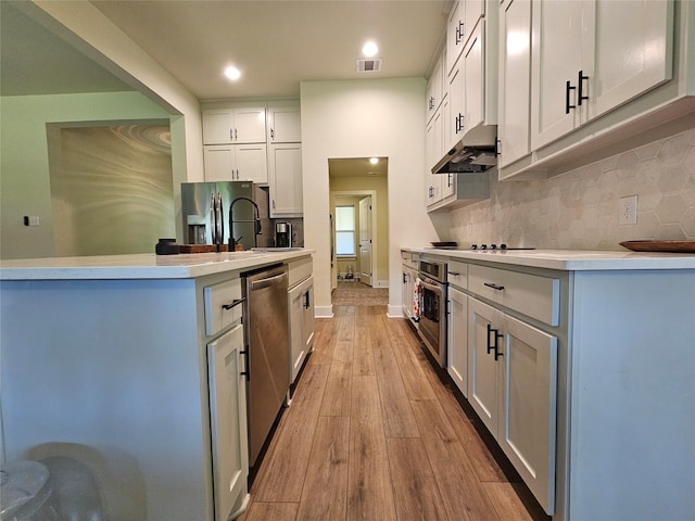 kitchen featuring under cabinet range hood, visible vents, light wood-style floors, light countertops, and appliances with stainless steel finishes