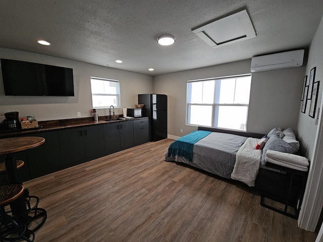 bedroom featuring attic access, dark wood finished floors, freestanding refrigerator, a wall mounted air conditioner, and a sink