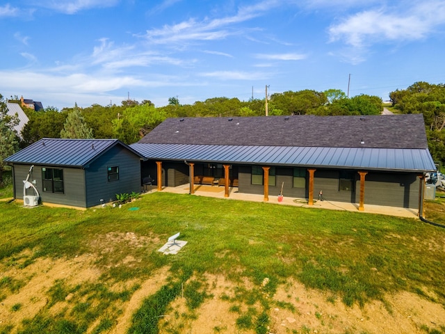 rear view of property with a standing seam roof, metal roof, a patio, and a yard