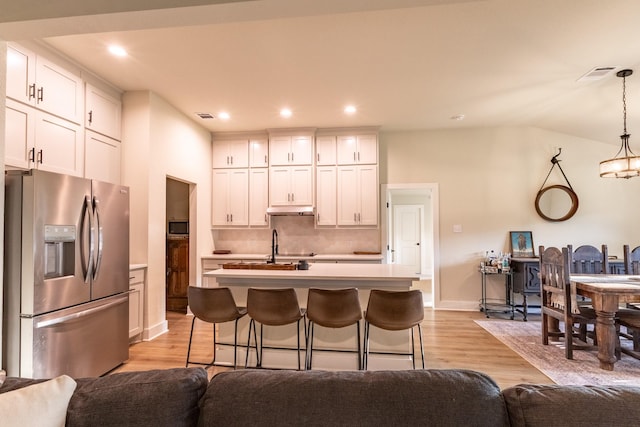 2040 Bluff Creek Dr, Strawn, TX 76475 - kitchen with under cabinet range hood, stainless steel refrigerator with ice dispenser, open floor plan, and visible vents