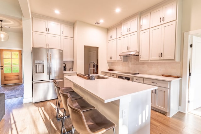 2040 Bluff Creek Dr, Strawn, TX 76475 - kitchen featuring stainless steel refrigerator with ice dispenser, an island with sink, under cabinet range hood, and light wood-type flooring
