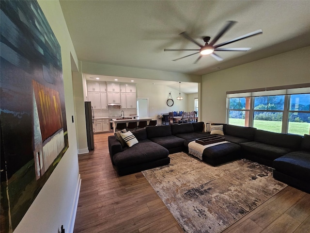 living area featuring baseboards, a ceiling fan, and hardwood / wood-style floors