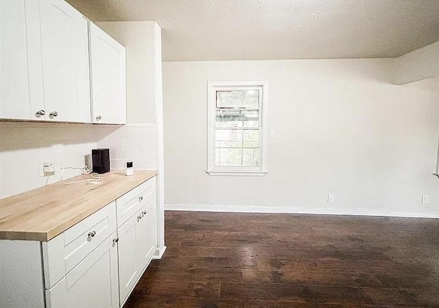 kitchen with wood counters, dark wood-type flooring, white cabinetry, and decorative backsplash