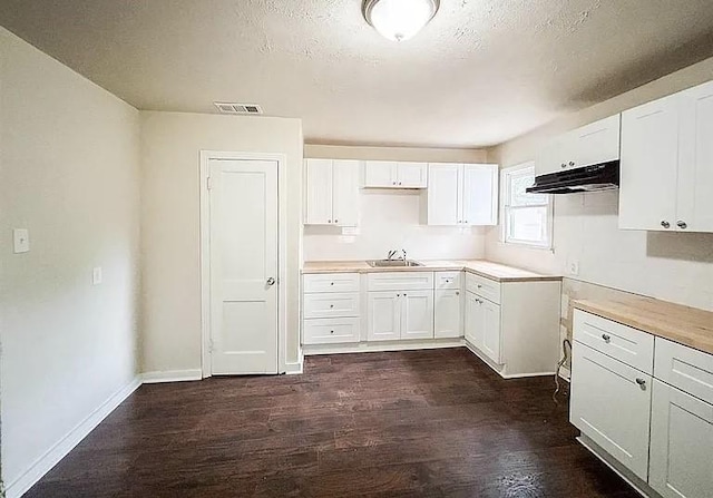 kitchen featuring sink, a textured ceiling, white cabinets, and dark hardwood / wood-style floors