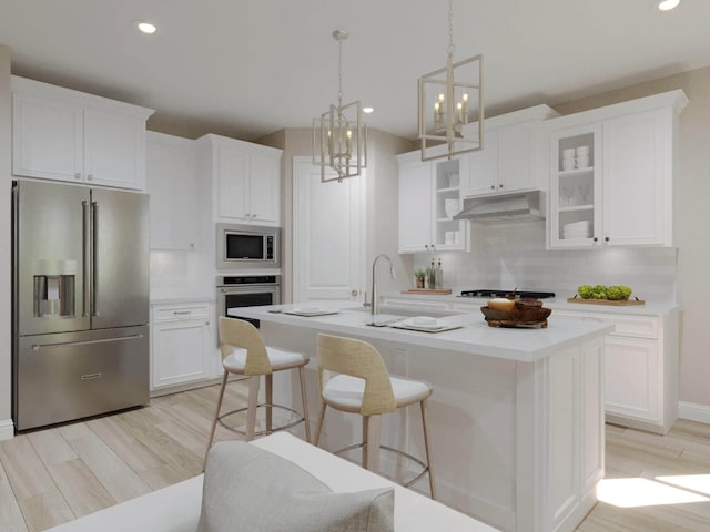 kitchen featuring appliances with stainless steel finishes, decorative backsplash, white cabinetry, and a center island with sink