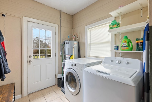 clothes washing area featuring laundry area, light tile patterned floors, washer and dryer, and water heater