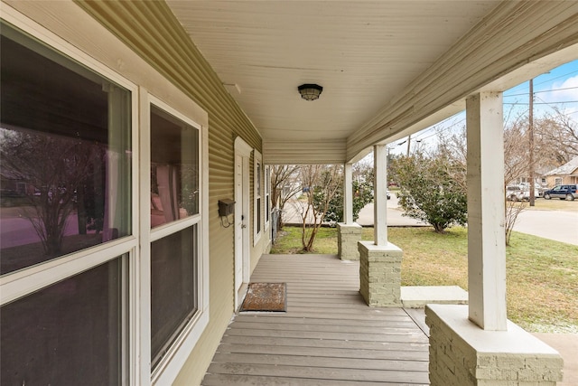 wooden terrace with a lawn and covered porch