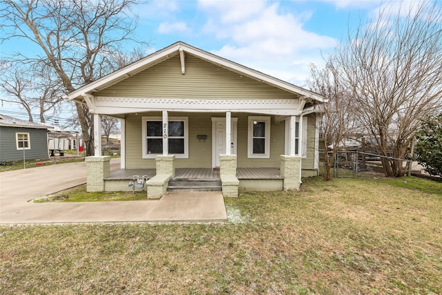 bungalow-style house with fence, a porch, and a front lawn