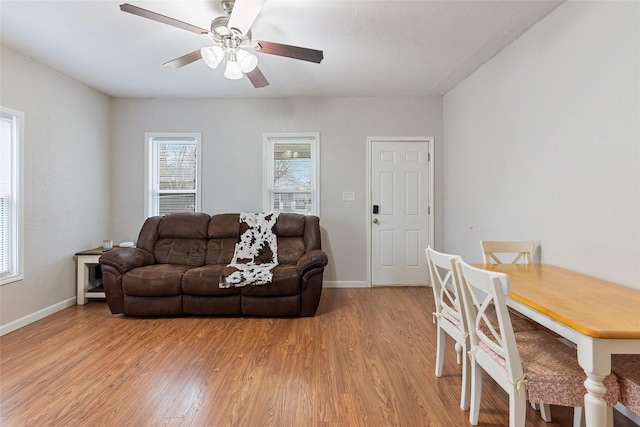 living area featuring baseboards, ceiling fan, and light wood finished floors