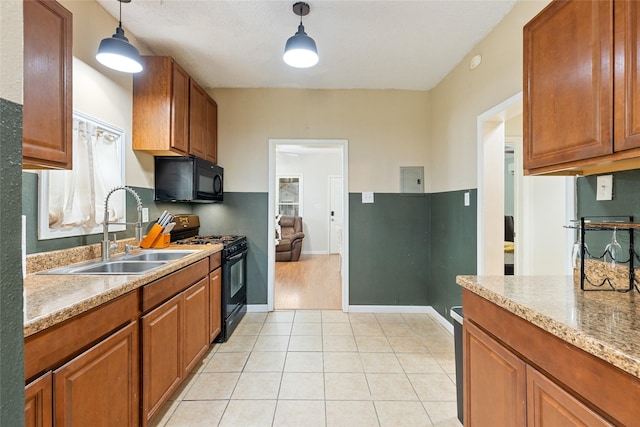 kitchen featuring a sink, light stone countertops, decorative light fixtures, black appliances, and brown cabinetry