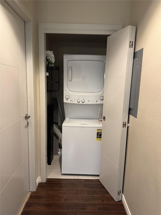 laundry room with stacked washer / dryer, laundry area, electric panel, and wood finished floors