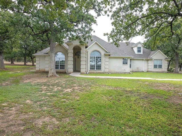 view of front facade featuring a shingled roof and a front yard