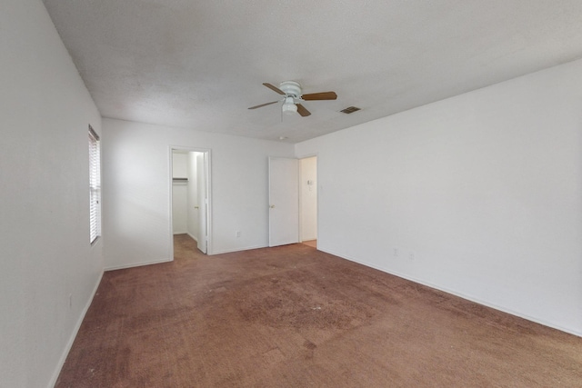 empty room with a ceiling fan, carpet, visible vents, and baseboards