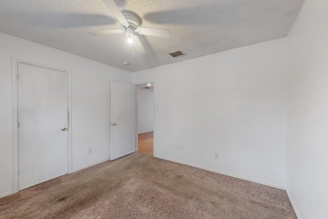 unfurnished bedroom featuring light carpet, ceiling fan, visible vents, and a textured ceiling