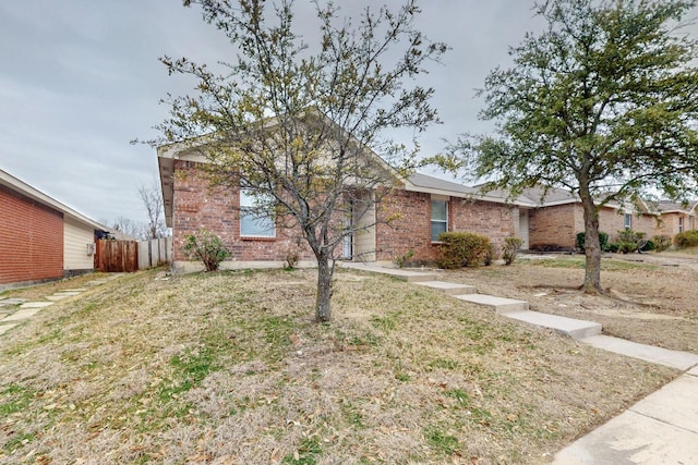 ranch-style house featuring a front yard, brick siding, and fence