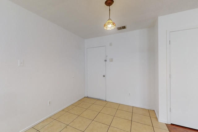 unfurnished room featuring light tile patterned floors, visible vents, and baseboards