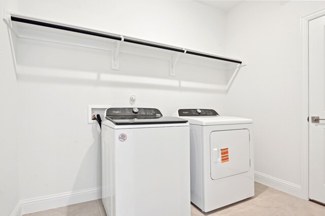 2321 Wellington Ln, Corinth, TX 76210 - clothes washing area with washing machine and clothes dryer, light tile patterned floors, and baseboards