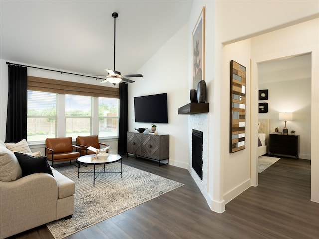 living room with ceiling fan, high vaulted ceiling, dark hardwood / wood-style flooring, and a stone fireplace