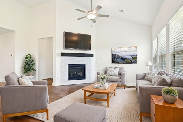 2321 Wellington Ln, Corinth, TX 76210 - living room featuring high vaulted ceiling, wood finished floors, a ceiling fan, a stone fireplace, and baseboards