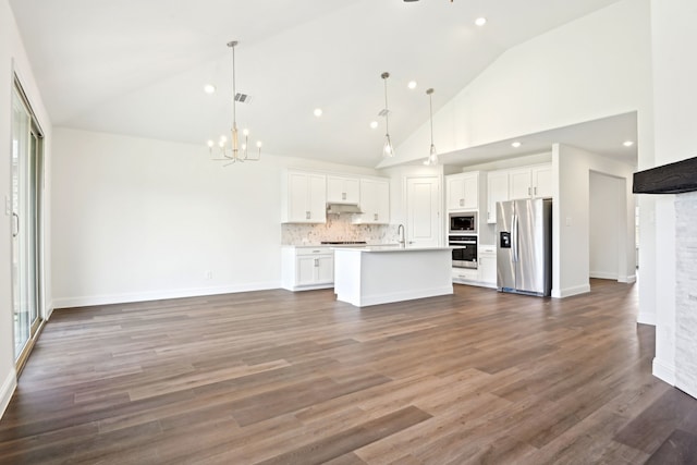 2321 Wellington Ln, Corinth, TX 76210 - kitchen featuring appliances with stainless steel finishes, high vaulted ceiling, open floor plan, a chandelier, and white cabinets