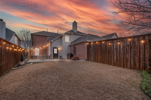 back house at dusk with a patio