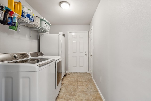 laundry area with laundry area, light tile patterned flooring, washing machine and clothes dryer, and baseboards