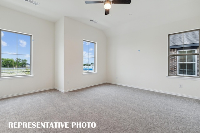 carpeted empty room with ceiling fan, plenty of natural light, and vaulted ceiling