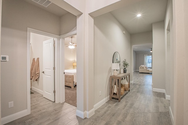 hallway with recessed lighting, wood finished floors, visible vents, and baseboards