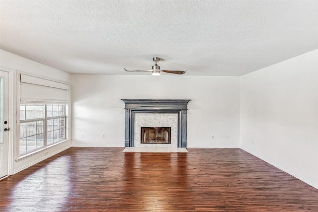 unfurnished living room with a fireplace, ceiling fan, dark hardwood / wood-style flooring, and a textured ceiling