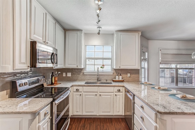 kitchen featuring sink, appliances with stainless steel finishes, white cabinetry, and light stone countertops