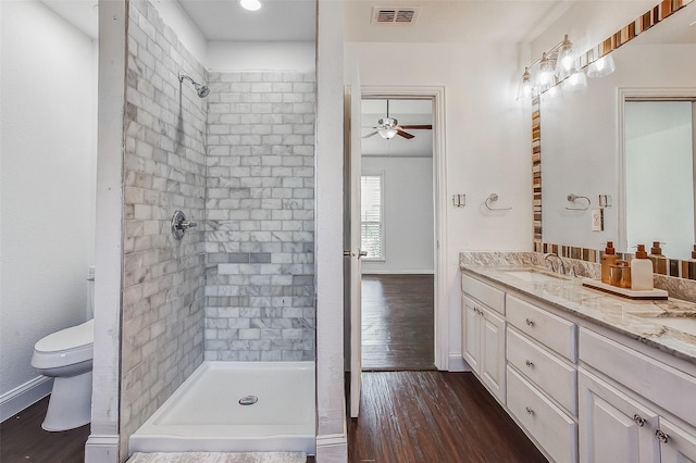 bathroom featuring vanity, a tile shower, ceiling fan, toilet, and hardwood / wood-style flooring