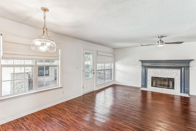 unfurnished living room featuring hardwood / wood-style flooring, ceiling fan, and a textured ceiling