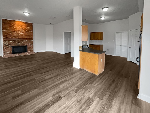 kitchen with a fireplace, dark wood-type flooring, sink, and kitchen peninsula