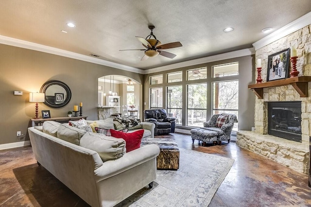 living room with a fireplace, ceiling fan, crown molding, and a textured ceiling