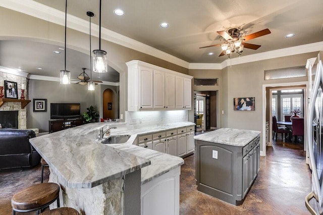 kitchen with a kitchen bar, sink, white cabinetry, kitchen peninsula, and hanging light fixtures