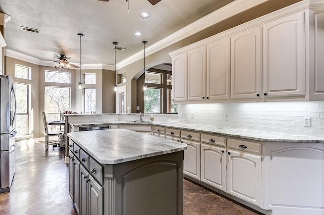 kitchen with white cabinets, a center island, pendant lighting, and ceiling fan